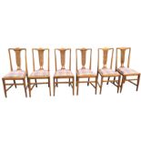 A set of six Edwardian oak dining chairs with shaped back rails above pierced splats, having tweed