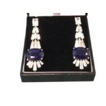 A pair of deco style sapphire drop earrings with oval claw set sapphires and baguette cut paste