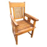 A hardwood armchair with portcullis style panel to barback, having rounded shaped arms above a