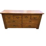 An oak cabinet of drawers with rectangular panelled top above a peg jointed front with four small