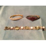 An oval yellow metal bangle, hinging in two halves and set with band of 29 pearls with beaded