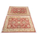 A pair of Egyptian made Persian style rugs having red fields of linked floral medallions framed by