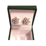 A pair of 9ct white gold diamond cluster earrings, set as flowerheads - each with seven diamonds,
