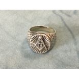 A silver gentlemans masonic signet ring with brick style shoulders framing an oval ribbed panel with