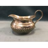 An oval hallmarked silver cream jug with gadrooned body and scrolled handle - JH Potter jug,