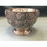 A Chinese silver bowl heavily embossed with flowers beneath a moulded rim, above a hammered scrolled