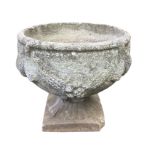 A circular bowl shaped composition stone urn moulded with swagged decoration on fluted support