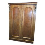 A Victorian mahogany wardrobe with concave cornice above arched panel doors with applied foliate