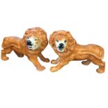 A pair of large late Victorian Staffordshire style lions, with painted faces and glass eyes - one