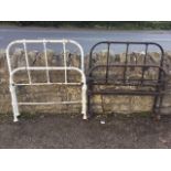 A pair of painted tubular iron bed-ends with rounded frames around vertical bars, raised on casters;