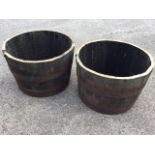 A pair of oak barrel planters, the staves bound by riveted metals trap bands. (24.5in x 17.25in) (