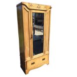 A late Victorian art nouveau ash wardrobe with stylised carving above a bevelled mirror door