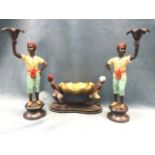 A pair of cold painted bronze candlesticks, modelled as young turbaned eastern chaps holding leaf