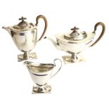 An Edwardian EPNS three-piece teaset of oval moulded tapering form having scrolled handles, raised