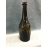 An eighteenth century olive glass wine bottle with ring to neck, having broad shoulders and inverted