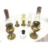 Two brass oil lamps with tubular glass chimneys; a milk glass oil lamp with brass mounts; a Farms