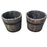 A pair of oak barrel type planters, the staves bound by two painted metal strap bands. (17.75in x