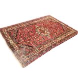 An oriental rug woven with central lozenge shaped medallion on busy red field framed by dotted