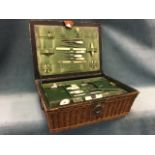 An Edwardian cane sewing basket with leather lid having fitted lined interior with implements,