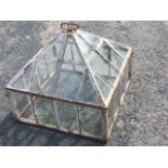 A square cast iron Victorian cloche with glazed panels and pitched roof surmounted by a carriage