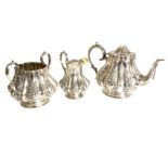 A Victorian silver three-piece teaset embossed with foliate decoration to fluted panels, having