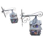 A pair of iron wall lamps with scrolled brackets supporting gabled house-like enclosures, fitted