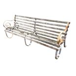 An Edwardian wrought iron garden bench, with three scrolled supports having slatted back & seat. (