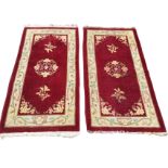 A pair of chinoiserie wool rugs, the maroon fields knotted with floral sprigs and spandrels,