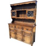 An oak dresser, the back with moulded cornice and shaped apron above open shelves flanked by