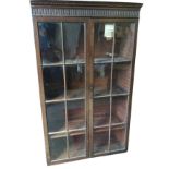 An Edwardian stained mahogany cupboard with fluted moulded cornice above astragal glazed doors