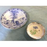 A large blue & white delft wallplaque depicting winter scene, with skaters on ice framed by