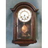 A small oak cased C20th wallclock with arched moulded cornice above a bevelled glass door