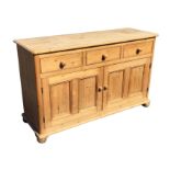 A pine dresser with rectangular rounded moulded top above three frieze drawers and panelled