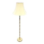 A brass standard lamp, with baluster turned column on circular weighted base, fitted with fabric