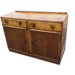 An oak sideboard with rectangular tray top above two frieze drawers and panelled cupboards, raised