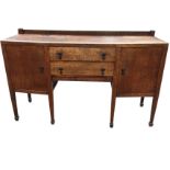 A bowfronted oak sideboard with carving to upstand, having crossbanded top above two central drawers