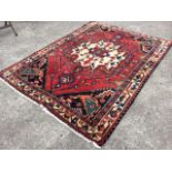 A Turkish rug woven with star shaped medallion on red ground with geometric stylised spandrels,