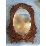 A Victorian carved oak mirror, the oval frame surmounted by dolphins issuing fruit, the base with
