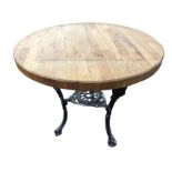 A circular pub table with oak top on three sabre legs cast with masques, the legs joined by