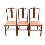A set of three Edwardian mahogany bedroom chairs having arched backs and shaped splats above