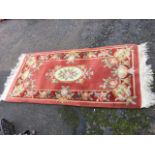 A Chinese thick pile wool rug woven with oval floral medallion on pink field framed by red