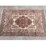 A fine Indian oriental rug woven with oval scalloped floral medallion on ivory ground with leaf