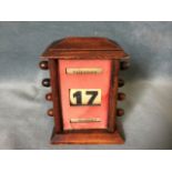 A Edwardian mahogany desk calendar, the case with pitched roof having three rollers under glass,