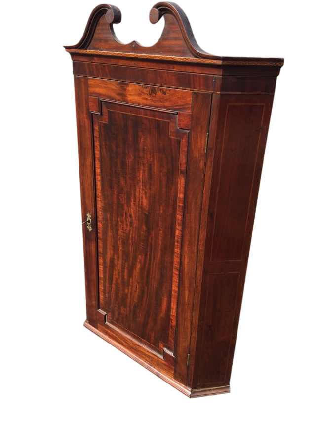 A Georgian mahogany corner cabinet with swan-neck pediment above a chequered inlaid band, having