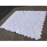 A patchwork quilt with scalloped edge, sewn with pink panels on pale floral ground. (78in x 99in)