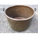 A large nineteenth century copper cauldron with tubular rim, riveted with oval lug handles. (20in