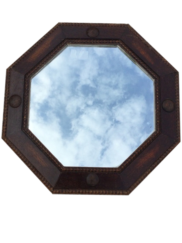 A 1930s octagonal oak mirror in bead moulded angled frame with applied roundels. (21in)