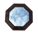 A 1930s octagonal oak mirror in bead moulded angled frame with applied roundels. (21in)