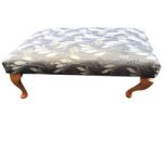 A rectangular upholstered stool on beech stub cabriole legs - one leg loose. (38in x 25in x 14in)