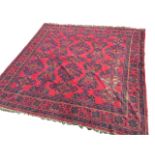 A square Turkey carpet woven in the traditional palette on red ground, the field with rows of
